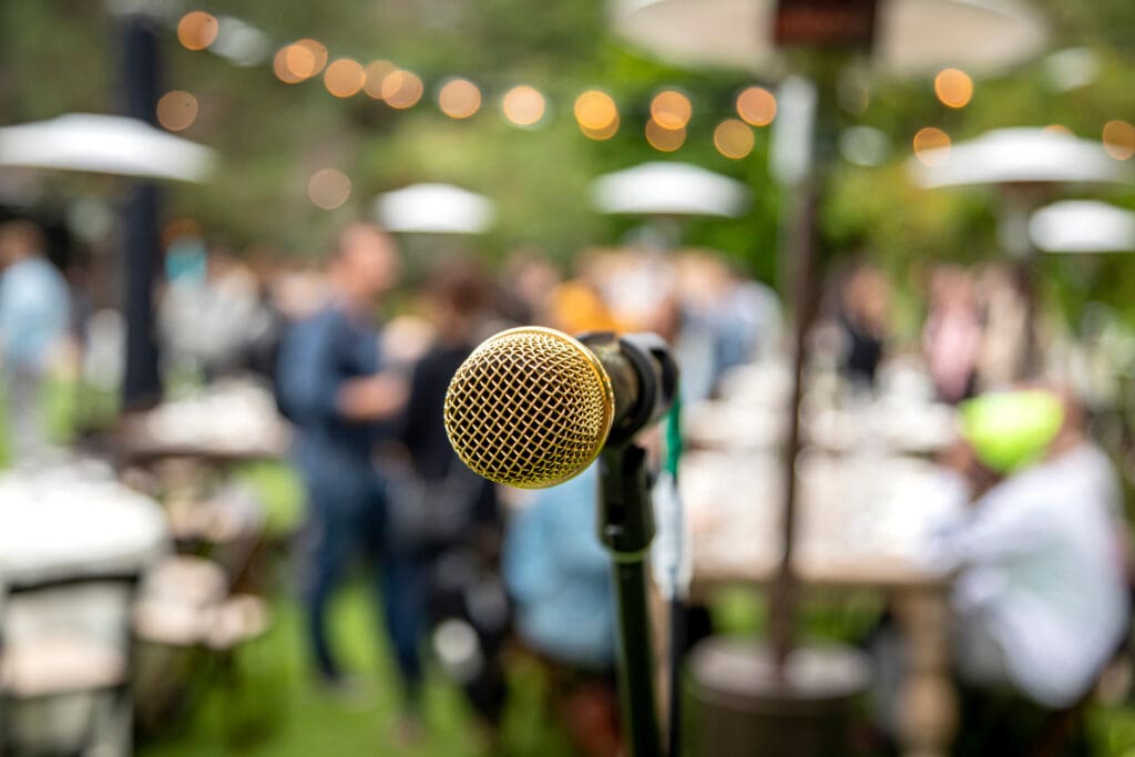 Close up of microphone at event with tables and people out of focus in the background